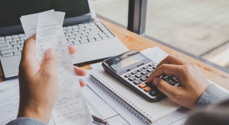 young-man-using-calculator-and-calculate-bills-in-home-office